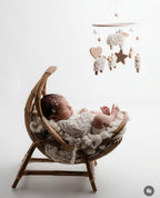 Newborn baby in a wicker basket with a mobile above, on a white background