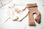 Knitted baby sweater with deer design and matching leggings on a wooden surface