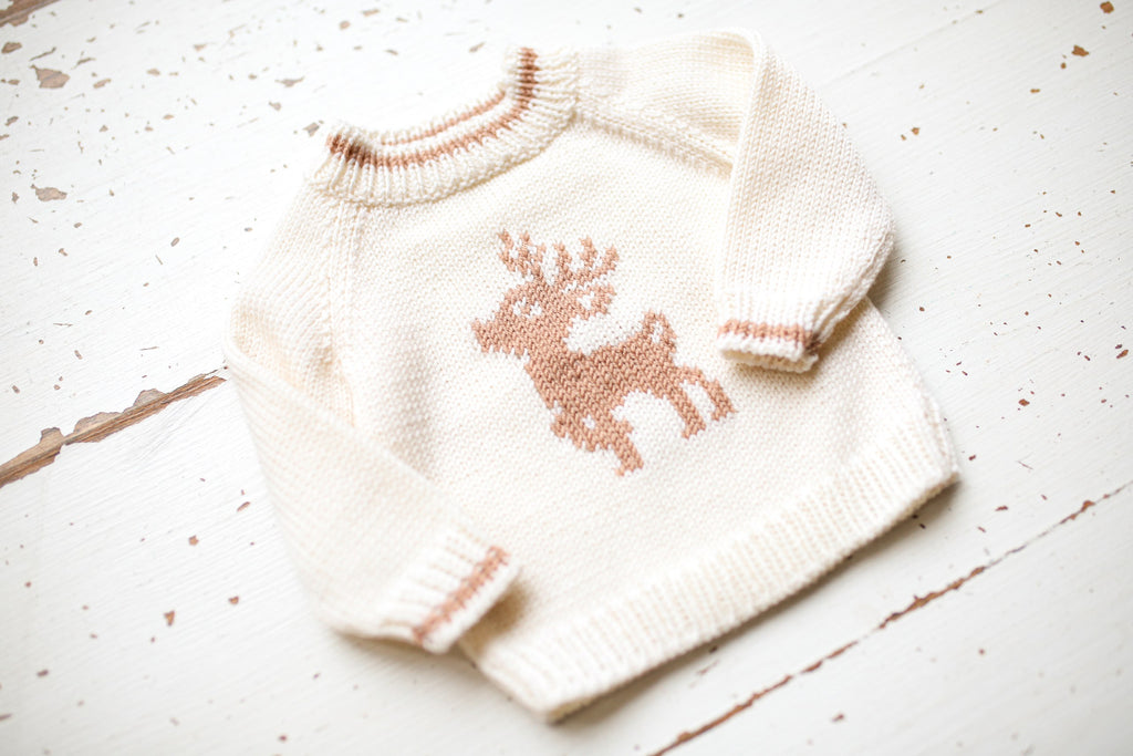 Knitted sweater with a reindeer design on a light wooden surface