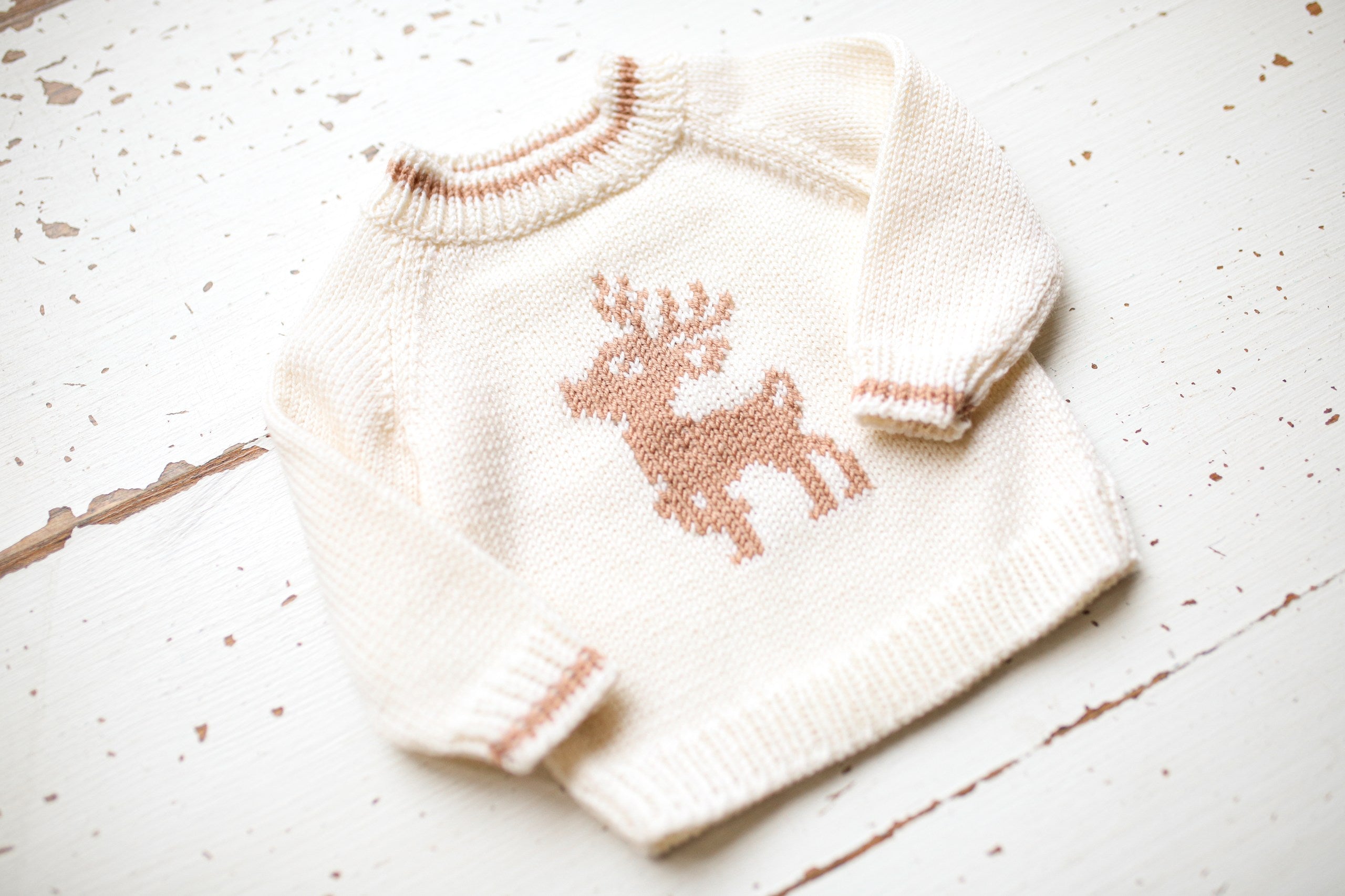 Knitted sweater with a reindeer design on a light wooden surface