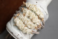 A newborn headband featuring a floral design with white fabric and lace, tied in a knot with brown strings.