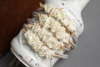 A newborn headband featuring a floral design with white fabric and lace, tied in a knot with brown strings.