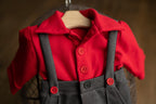 A newborn boy romper with suspenders and a stylish hat placed on a wooden surface.