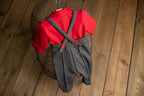 A newborn boy romper with suspenders and a stylish hat placed on a wooden surface.