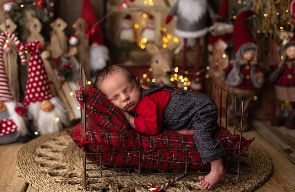A newborn boy romper with suspenders and a stylish hat placed on a wooden surface.